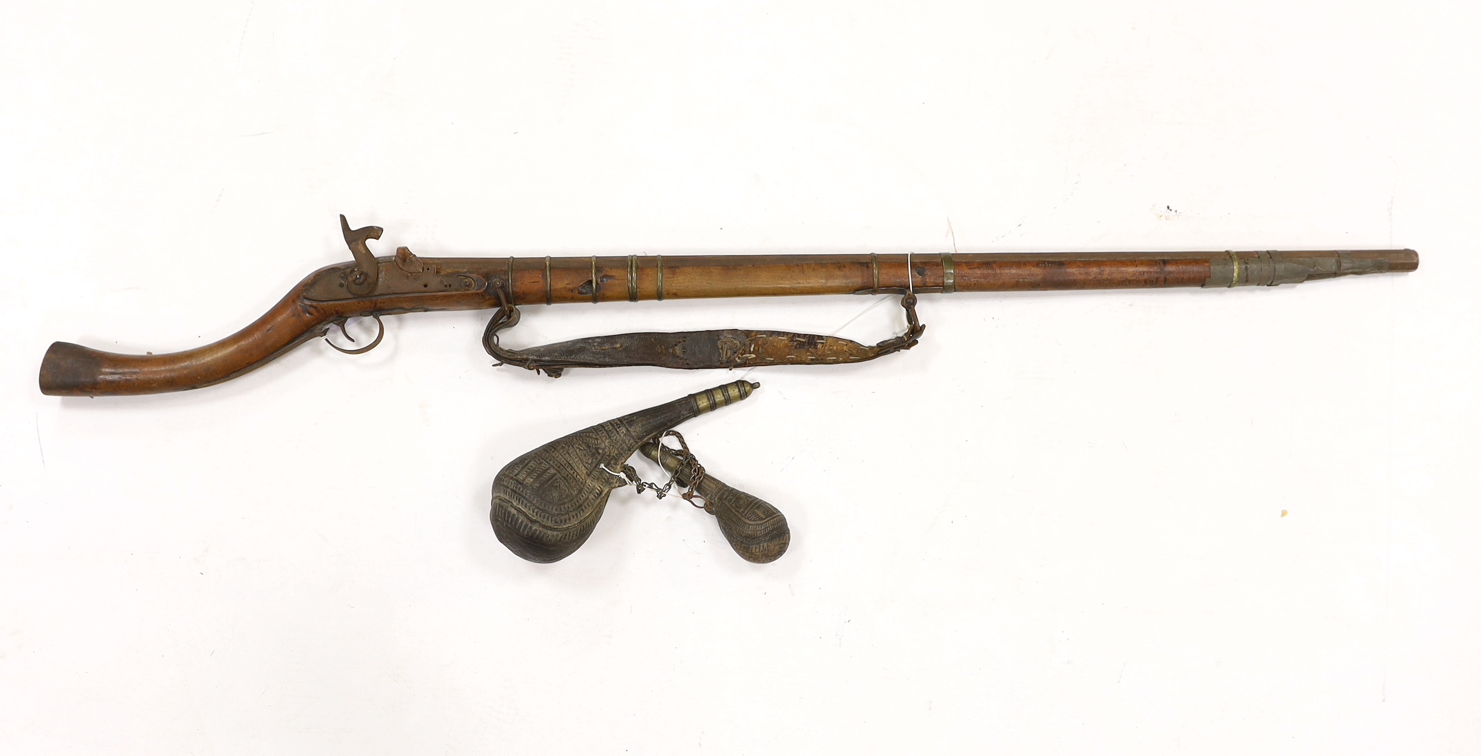 An Afghan percussion rifle with octagonal barrel and brass mounts, barrel 105.5cm, together with two leather powder flasks